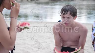 孩子们，青少年在海滩上休息，笑着<strong>吃西瓜</strong>，慢动作<strong>视频</strong>。 男孩和女孩休息